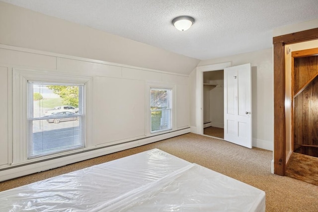 bedroom featuring carpet floors, a baseboard heating unit, vaulted ceiling, a textured ceiling, and a closet