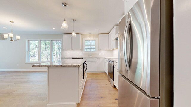 9 Country Dr, Old Orchard Beach, ME 04064 - kitchen with stainless steel appliances, a center island, decorative backsplash, light wood-type flooring, and light stone countertops