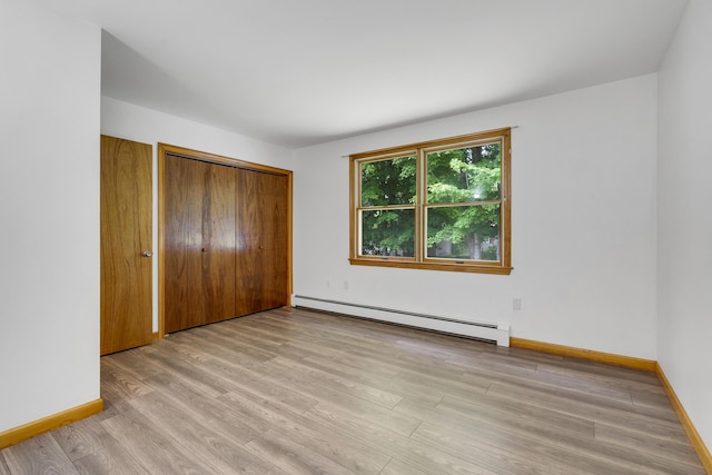 32 Thorne Ave, Lewiston, ME 04240 - unfurnished bedroom featuring baseboard heating, light wood-type flooring, baseboards, and a closet