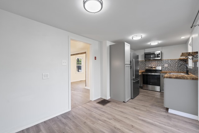 441 Middle Rd, Woolwich, ME 04579 - kitchen featuring stainless steel appliances, light wood finished floors, tasteful backsplash, and baseboards