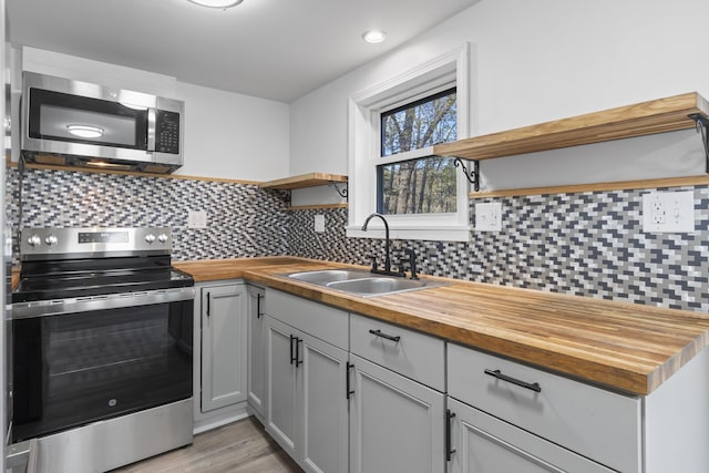 441 Middle Rd, Woolwich, ME 04579 - kitchen with appliances with stainless steel finishes, open shelves, wood counters, a sink, and decorative backsplash