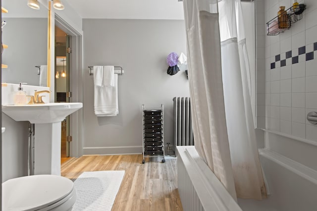 66 Spruce St Unit 1, Portland, ME 04102 - bathroom featuring radiator, wood finished floors, shower / bath combo with shower curtain, toilet, and baseboards