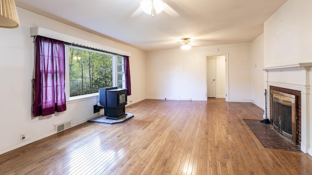 13 Packard Ave, Norway, ME 04268 - unfurnished living room with a wood stove, ceiling fan, hardwood / wood-style floors, and a fireplace