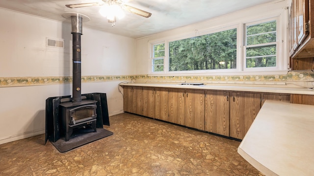 13 Packard Ave, Norway, ME 04268 - kitchen with brown cabinets, light countertops, a wood stove, a ceiling fan, and crown molding