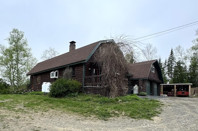 135 W Conroy Lake Rd, Monticello, ME 04760 - view of property exterior featuring driveway, a chimney, a shingled roof, and a carport