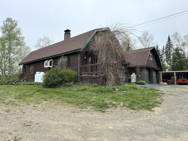 135 W Conroy Lake Rd, Monticello, ME 04760 - view of side of home with driveway, a shingled roof, a chimney, and a carport