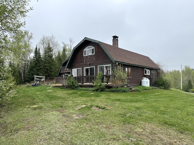 135 W Conroy Lake Rd, Monticello, ME 04760 - back of house with a gambrel roof, a chimney, a lawn, a deck, and a shingled roof