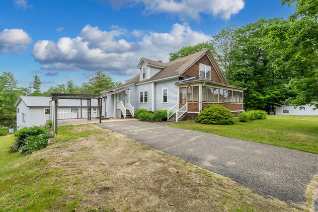 24 Emery Corner Rd, Limerick, ME 04048 - view of front of home with a sunroom, asphalt driveway, a front yard, and a shingled roof