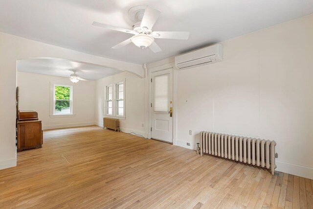 24 Emery Corner Rd, Limerick, ME 04048 - unfurnished living room with radiator, a wall unit AC, ceiling fan, and light wood-type flooring