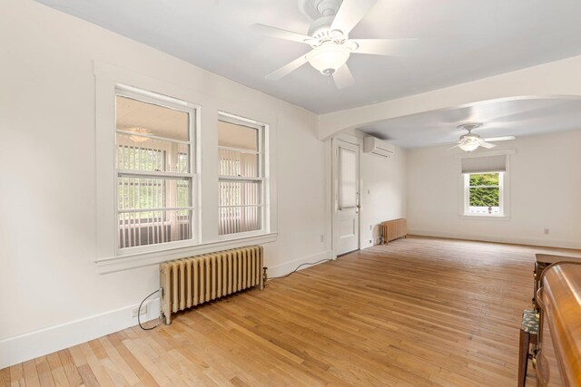 24 Emery Corner Rd, Limerick, ME 04048 - empty room with radiator heating unit, an AC wall unit, ceiling fan, and light wood-type flooring