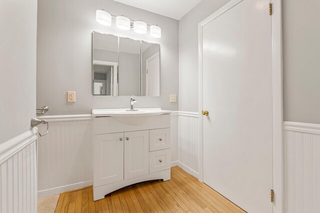 24 Emery Corner Rd, Limerick, ME 04048 - bathroom with wainscoting, hardwood / wood-style floors, vanity, and a decorative wall