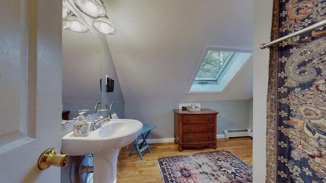 72 Sand Beach Rd, Standish, ME 04084 - bathroom with a baseboard radiator, a skylight, wood finished floors, and vaulted ceiling