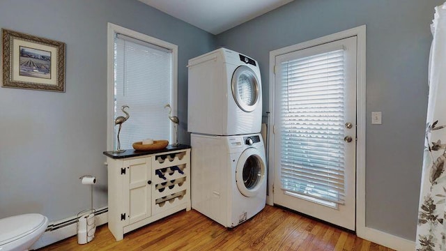 72 Sand Beach Rd, Standish, ME 04084 - clothes washing area with stacked washing machine and dryer, healthy amount of natural light, light wood-style flooring, and a baseboard radiator