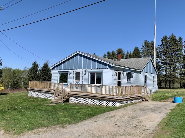 11 Brewster Rd, Eastport, ME 04631 - view of front of home featuring board and batten siding, a deck, a chimney, and a front yard