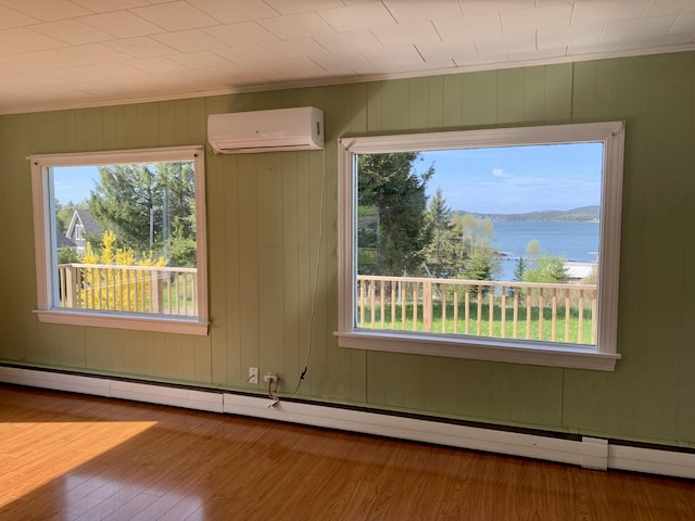 11 Brewster Rd, Eastport, ME 04631 - empty room featuring a wall mounted air conditioner, wood finished floors, a baseboard heating unit, a water view, and ornamental molding