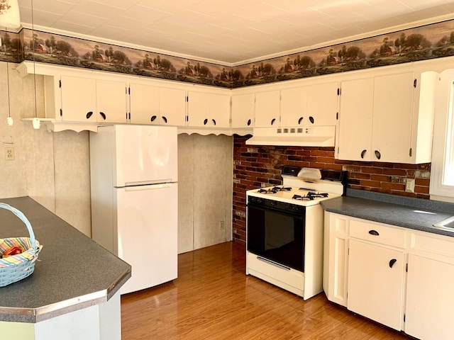 11 Brewster Rd, Eastport, ME 04631 - kitchen featuring gas range oven, freestanding refrigerator, under cabinet range hood, dark countertops, and light wood-style floors