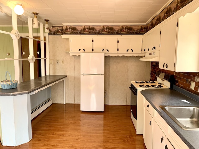 11 Brewster Rd, Eastport, ME 04631 - kitchen featuring white appliances, under cabinet range hood, baseboard heating, dark countertops, and a sink