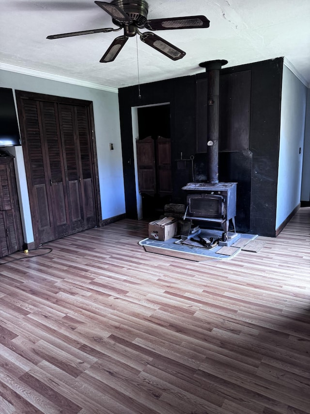 1596 Bald Mountain Rd, Orland, ME 04472 - living area with baseboards, a ceiling fan, wood finished floors, a wood stove, and ornamental molding