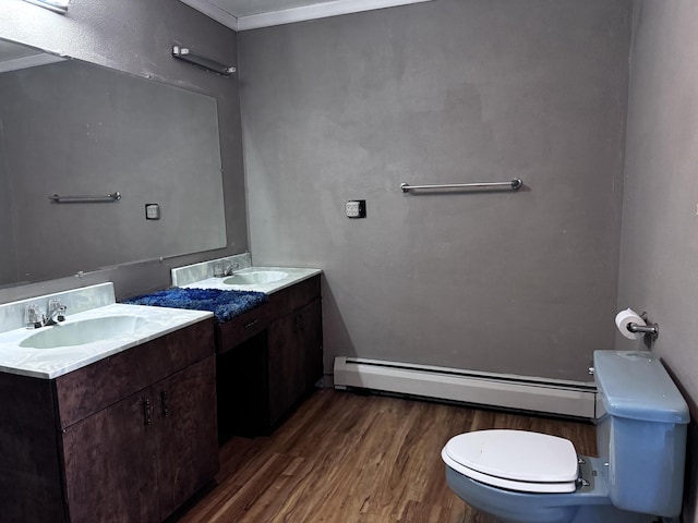 1596 Bald Mountain Rd, Orland, ME 04472 - bathroom with a baseboard radiator, wood finished floors, toilet, two vanities, and ornamental molding