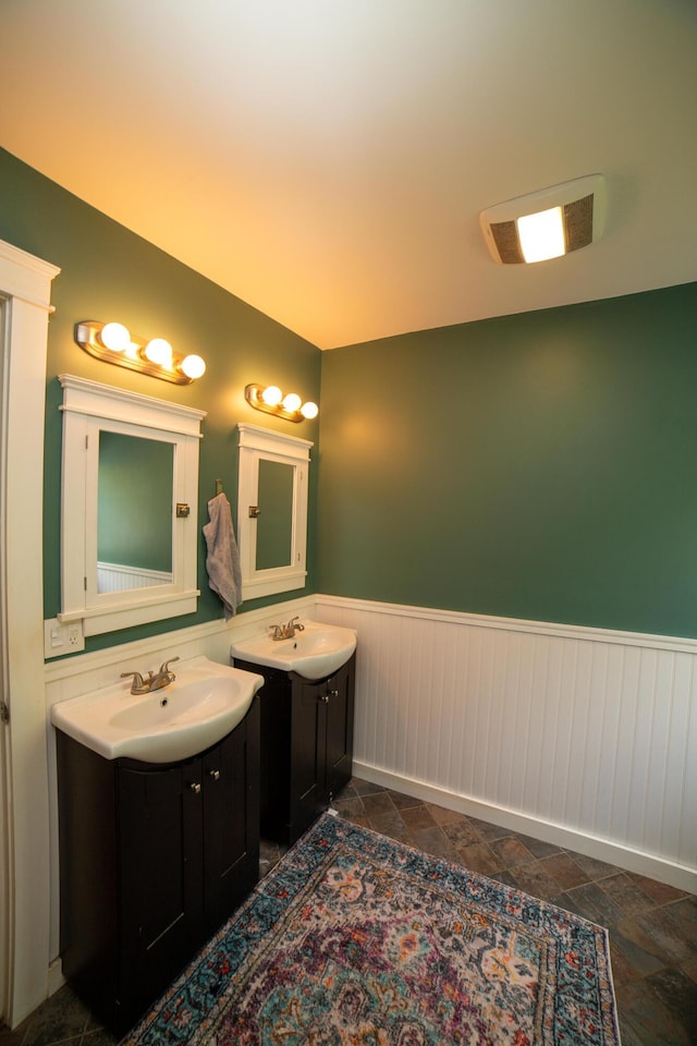 51 Brookview Dr, Bucksport, ME 04416 - bathroom with two vanities, a wainscoted wall, and stone tile flooring