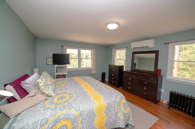 51 Brookview Dr, Bucksport, ME 04416 - bedroom featuring radiator heating unit, a wall mounted air conditioner, multiple windows, and wood finished floors