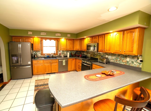 51 Brookview Dr, Bucksport, ME 04416 - kitchen featuring appliances with stainless steel finishes, a breakfast bar, a peninsula, tasteful backsplash, and brown cabinetry