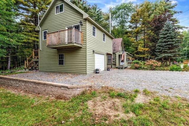 19 Birch Ests, Rome, ME 04963 - back of property with gravel driveway, a balcony, an attached garage, stairs, and log veneer siding