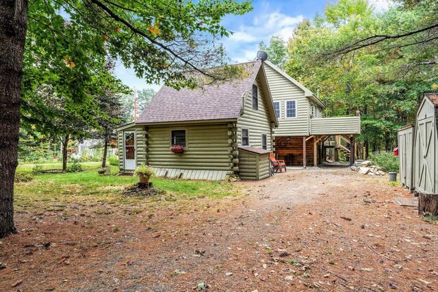 19 Birch Ests, Rome, ME 04963 - view of side of home featuring log exterior, stairway, driveway, an outbuilding, and a shingled roof