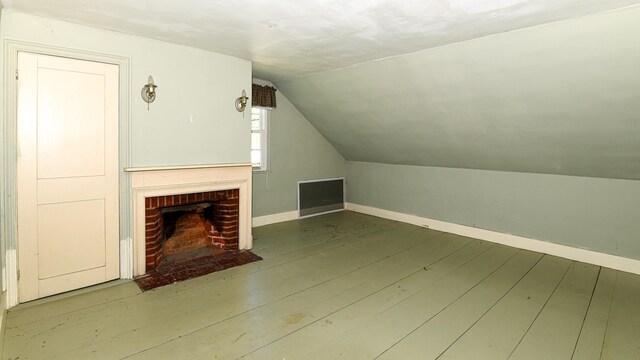43 Main St, Harrison, ME 04040 - unfurnished living room featuring lofted ceiling, wood finished floors, a brick fireplace, and baseboards