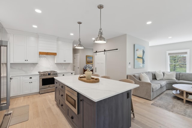6 Roberts Ln, Kennebunkport, ME 04046 - kitchen with appliances with stainless steel finishes, a barn door, white cabinetry, a center island, and light wood finished floors