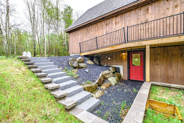 entrance to property featuring roof with shingles and a deck