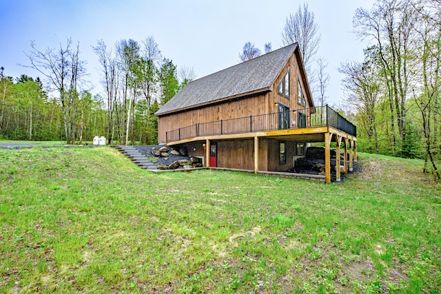 view of side of property with a deck, a lawn, and a shingled roof
