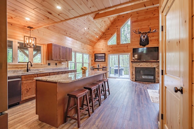 kitchen featuring stainless steel dishwasher, a sink, wood ceiling, brown cabinets, and a fireplace