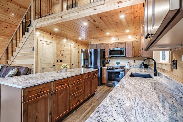 kitchen with appliances with stainless steel finishes, a sink, wood ceiling, wood finished floors, and a kitchen island