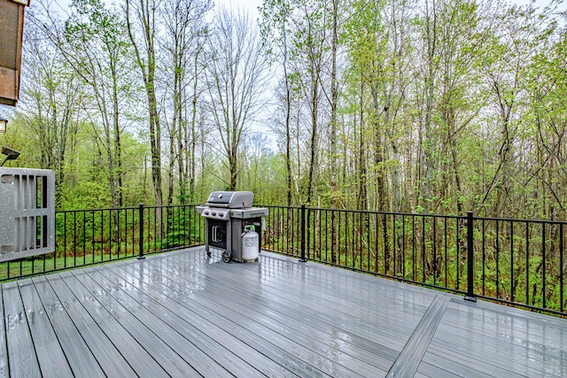 wooden deck with area for grilling and a view of trees