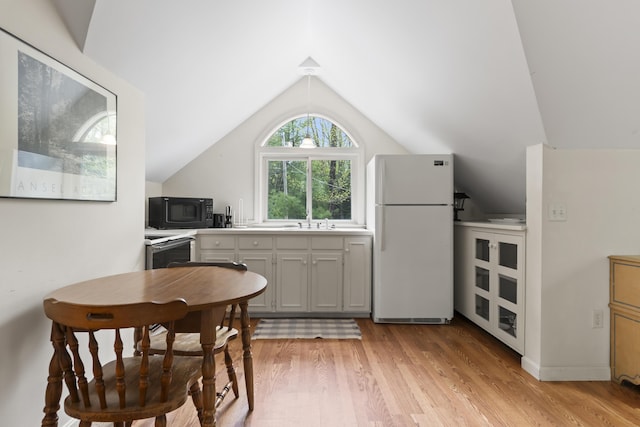 62 Lady Slipper Ln, Weld, ME 04285 - kitchen with freestanding refrigerator, black microwave, a sink, vaulted ceiling, and light wood finished floors