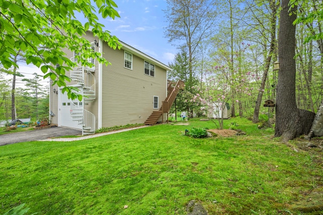 view of grassy yard featuring stairway, driveway, and a garage