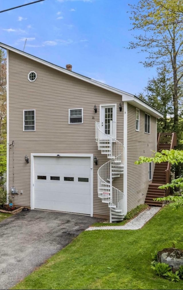back of house featuring stairs, a garage, driveway, and a lawn