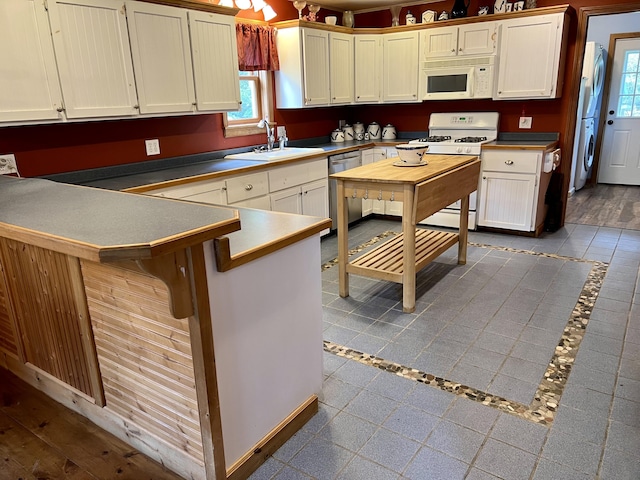 15 Miles Rd, Tremont, ME 04674 - kitchen with white appliances, inlaid floor details, a sink, washer / dryer, and a peninsula