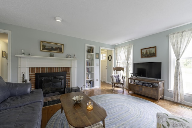 7 Salmon Run, Raymond, ME 04071 - living room featuring a fireplace, wood finished floors, built in shelves, and baseboards