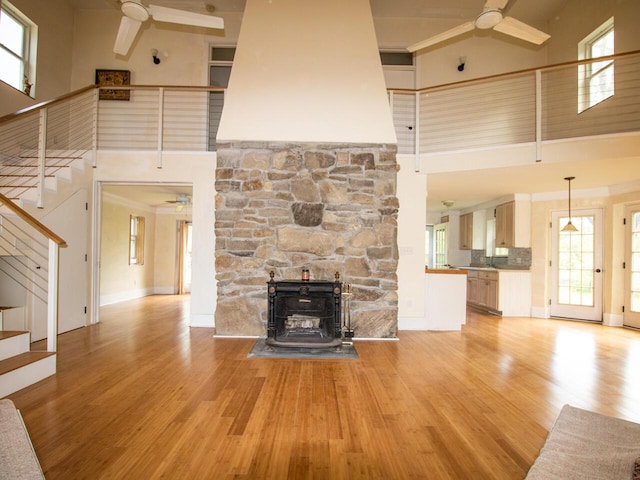 9 Juniper Ln, Damariscotta, ME 04543 - unfurnished living room featuring a ceiling fan, a high ceiling, stairs, light wood-style floors, and baseboards