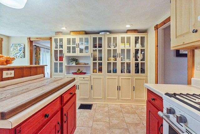 286 Canaan Rd, Clinton, ME 04927 - kitchen with light countertops, light tile patterned flooring, a textured ceiling, glass insert cabinets, and white range with gas cooktop