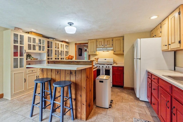 286 Canaan Rd, Clinton, ME 04927 - kitchen featuring under cabinet range hood, stainless steel range with gas cooktop, a kitchen island, a kitchen bar, and light countertops