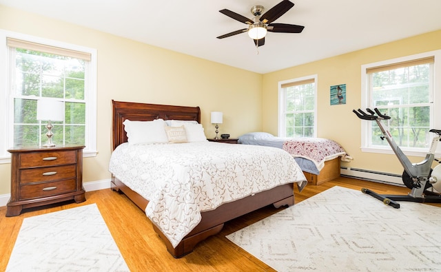 239 Cider Hill Rd, York, ME 03909 - bedroom featuring a baseboard heating unit, light wood-style flooring, baseboards, and ceiling fan
