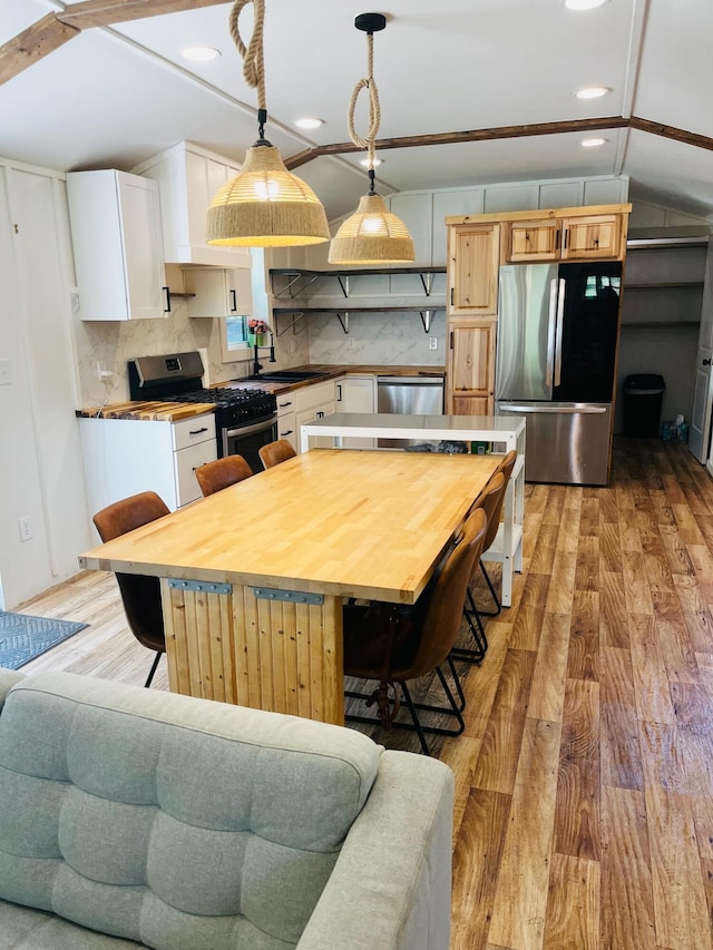 486 Main St, Orono, ME 04473 - kitchen with stainless steel appliances, light wood finished floors, white cabinets, a sink, and pendant lighting