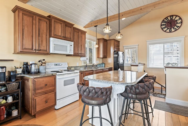 159 Loop Rd, Acton, ME 04001 - kitchen with white appliances, a kitchen island, light wood-type flooring, a kitchen bar, and light stone counters