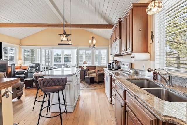 159 Loop Rd, Acton, ME 04001 - kitchen featuring open floor plan, white appliances, brown cabinetry, a sink, and a kitchen breakfast bar