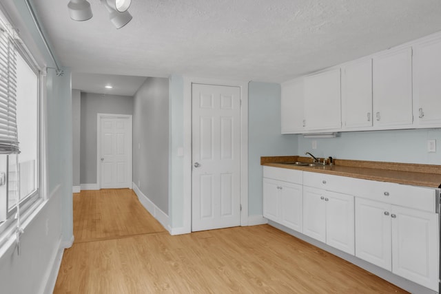 138 Summer St, Biddeford, ME 04005 - kitchen with a sink, light wood-style flooring, a textured ceiling, and white cabinets