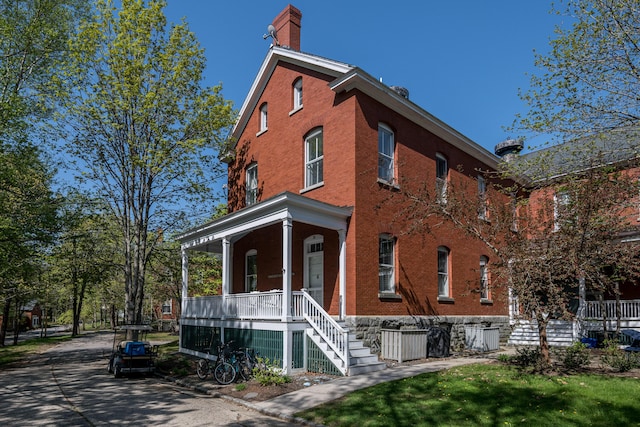 28 Ingalls Rd Unit 28, Portland, ME 04109 - view of home's exterior featuring covered porch, brick siding, a chimney, and stairway