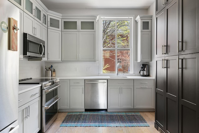 28 Ingalls Rd Unit 28, Portland, ME 04109 - kitchen with stainless steel appliances, a sink, light countertops, decorative backsplash, and light wood-style flooring